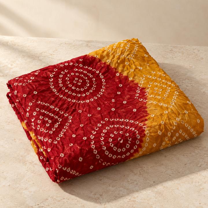 Folded red and yellow fabric with dotted circular tie-dye patterns