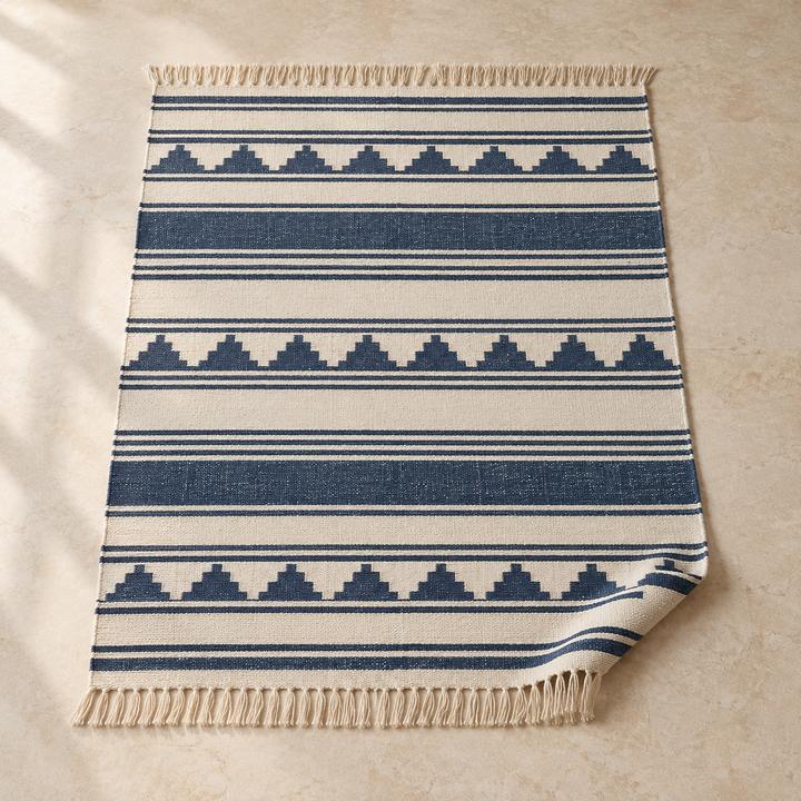 Flat-woven rug with blue and white stripes and fringed ends