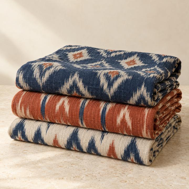 Three folded fabrics in blue and rust with blurred diamond patterns