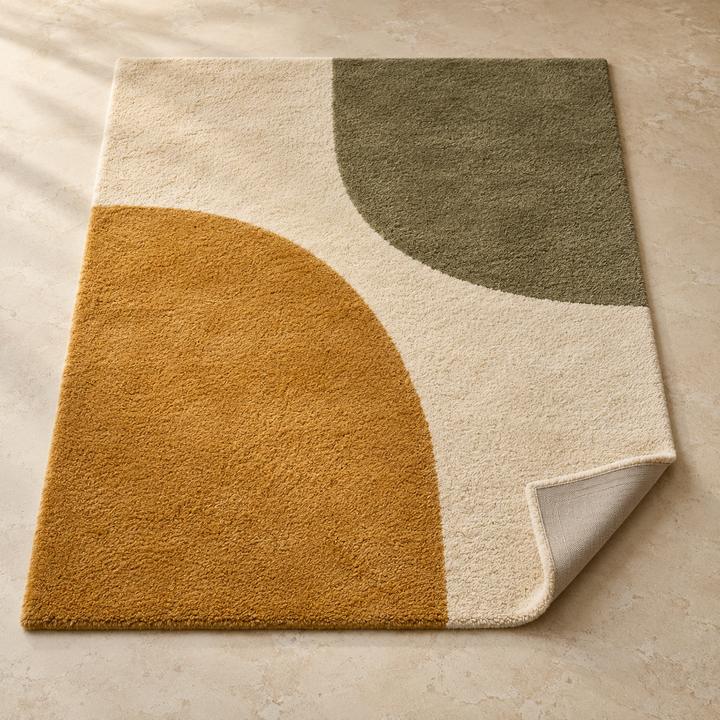 Modern rug with cream, mustard and olive curved shapes, one corner turned up